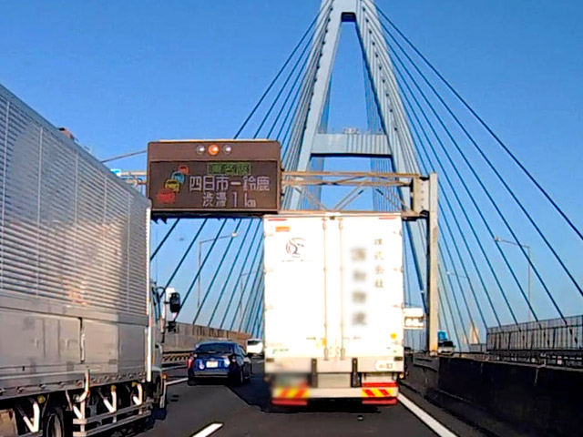 青い橋、名港潮見ICの手前の電光掲示板は「東名阪 四日市－鈴鹿 渋滞1km」と鈴鹿IC出口渋滞を知らせている