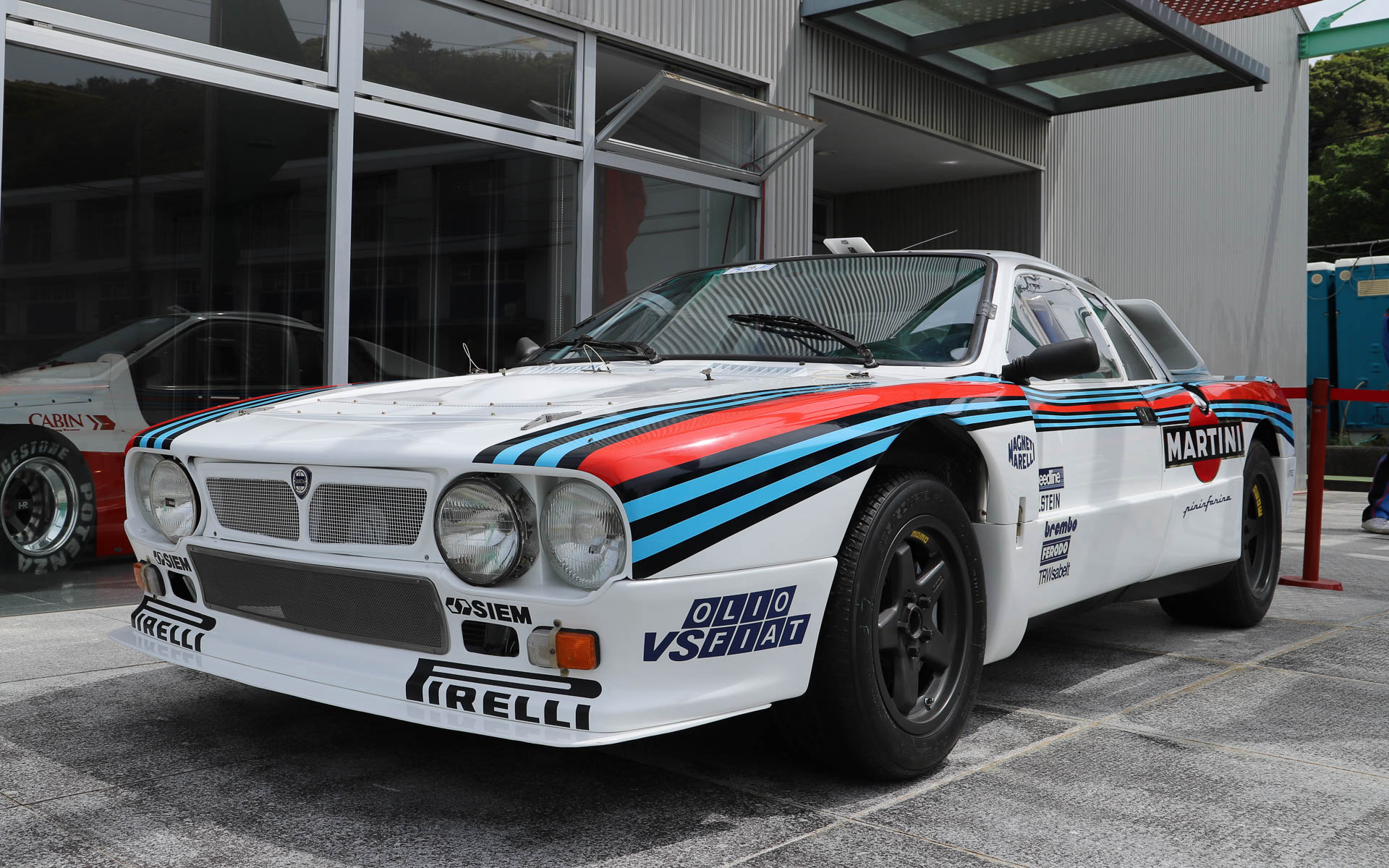 「ランチア・ラリー037」。4WDが台頭してきた1980年代のWRCに、あえてミッドシップで挑んだ車両。過酷なレースのため、現存するワークスマシンは約半数と言われている。デザインはピニンファリーナが担当した。ボディはケブラーとカーボンファイバーで構成され、当時としてはかなり軽量とされている。整備性を高めるため、エンジンルームへのアクセスがしやすいような工夫がされており、ボンネットはパイプ1本で支えるだけとなっている。エンジンは「アバルト・131」の直列4気筒エンジンをベースにチューニングし、スーパーチャージャーを搭載することで、低回転域からパワーを発揮する