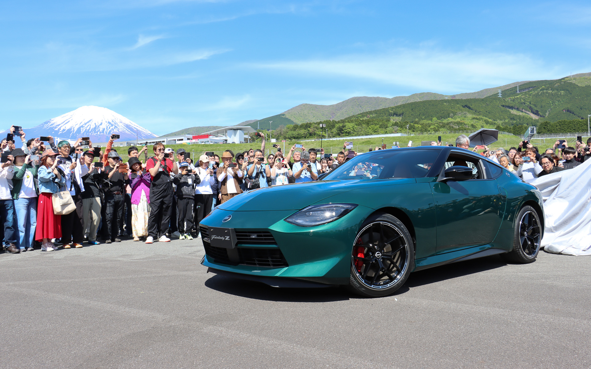 オーナーズミーティングに参加した歴代Zオーナーが見守るなか、日産自動車株式会社 グローバルデザイン本部 アドバンスドデザイン部 主管 森田充儀氏（左）と日産自動車株式会社 プログラムデザインダイレクター 入江慎一郎氏（右）の2人の手でフェアレディZ マイナーチェンジモデルがアンベールされた