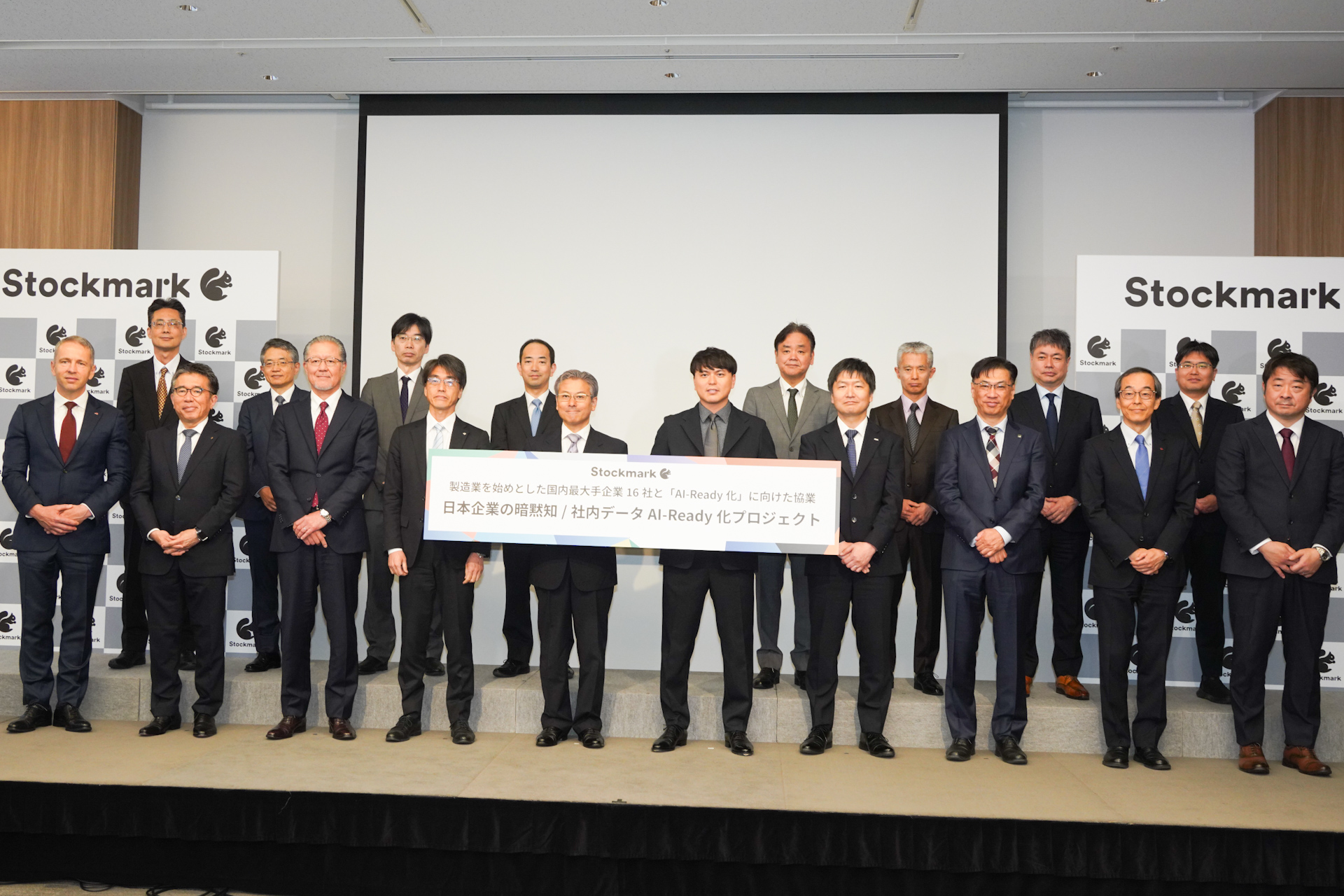 発表会登壇者。前列左から、味の素株式会社 執行役常務 CDO スムリガ・ミロスラブ氏、伊藤忠商事株式会社 准執行役員 IT・デジタル戦略部長 浦上善一郎氏、NGK株式会社 取締役専務執行役員 森潤氏、株式会社神戸製鋼所 執行役員 入谷一夫氏、経済産業省大臣官房審議官（商務情報政策局担当） 奥家敏和氏、ストックマーク株式会社 代表取締役CEO 林達氏、株式会社ジェイテクト 研究開発センター長 小野崎徹氏、スズキ株式会社 常務役員 IT本部長 野中彰氏、住友化学株式会社 常務理事 DX推進室長 土佐泰夫氏、太陽誘電株式会社 開発研究所 開発企画部 茂木昌詩氏。写真後列左から、帝人株式会社 CTO補佐 尾崎大介氏、東京電力ホールディングス株式会社 常務執行役 関知道氏、日揮ホールディングス株式会社 執行役員 CDO 谷川圭史氏、株式会社三井住友銀行 執行役員 八木修氏、三菱ケミカル株式会社 執行役員 チーフデジタルオフィサー 浦本直彦氏、ヤンマーホールディングス株式会社 取締役 経営戦略・技術・DX担当 奥山博史氏、ライオン株式会社 執行役員 全社デジタル戦略担当、デジタル戦略部担当 中林紀彦氏、株式会社LIXIL 常務役員 CX部門 リーダー 安井卓氏