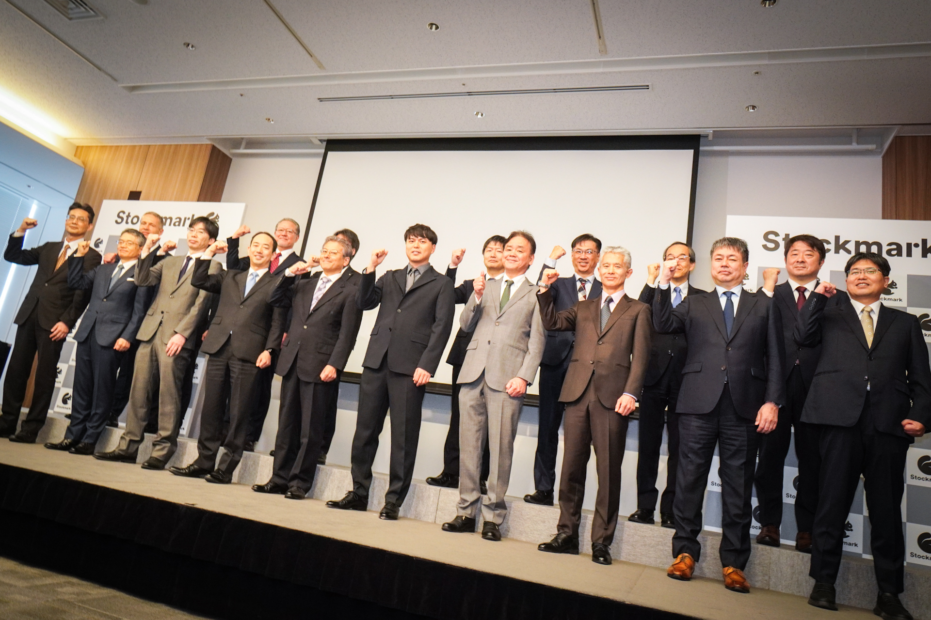 発表会登壇者。写真前列左から、帝人株式会社 CTO補佐 尾崎大介氏、東京電力ホールディングス株式会社 常務執行役 関知道氏、日揮ホールディングス株式会社 執行役員 CDO 谷川圭史氏、株式会社三井住友銀行 執行役員 八木修氏、経済産業省大臣官房審議官（商務情報政策局担当） 奥家敏和氏、ストックマーク株式会社 代表取締役CEO 林達氏、三菱ケミカル株式会社 執行役員 チーフデジタルオフィサー 浦本直彦氏、ヤンマーホールディングス株式会社 取締役 経営戦略・技術・DX担当 奥山博史氏、ライオン株式会社 執行役員 全社デジタル戦略担当、デジタル戦略部担当 中林紀彦氏、株式会社LIXIL 常務役員 CX部門 リーダー 安井卓氏。写真後列左から、味の素株式会社 執行役常務 CDO スムリガ・ミロスラブ氏、伊藤忠商事株式会社 准執行役員 IT・デジタル戦略部長 浦上善一郎氏、NGK株式会社 取締役専務執行役員 森潤氏、株式会社神戸製鋼所 執行役員 入谷一夫氏、株式会社ジェイテクト 研究開発センター長 小野崎徹氏、スズキ株式会社 常務役員 IT本部長 野中彰氏、住友化学株式会社 常務理事 DX推進室長 土佐泰夫氏、太陽誘電株式会社 開発研究所 開発企画部 茂木昌詩氏