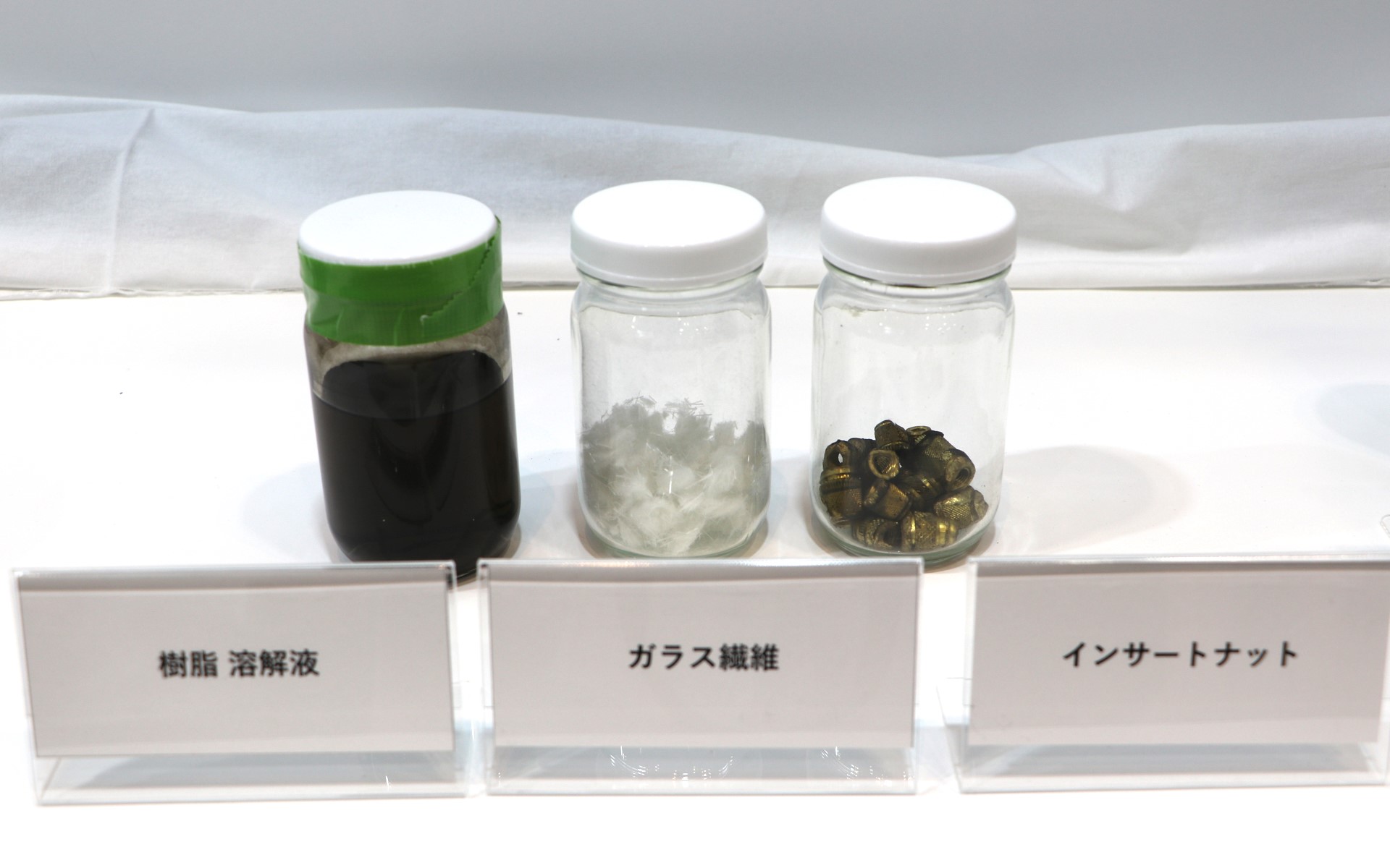 左から、溶媒で樹脂を溶かした液体。分離抽出されたガラス繊維、分離抽出されたインサートナット
