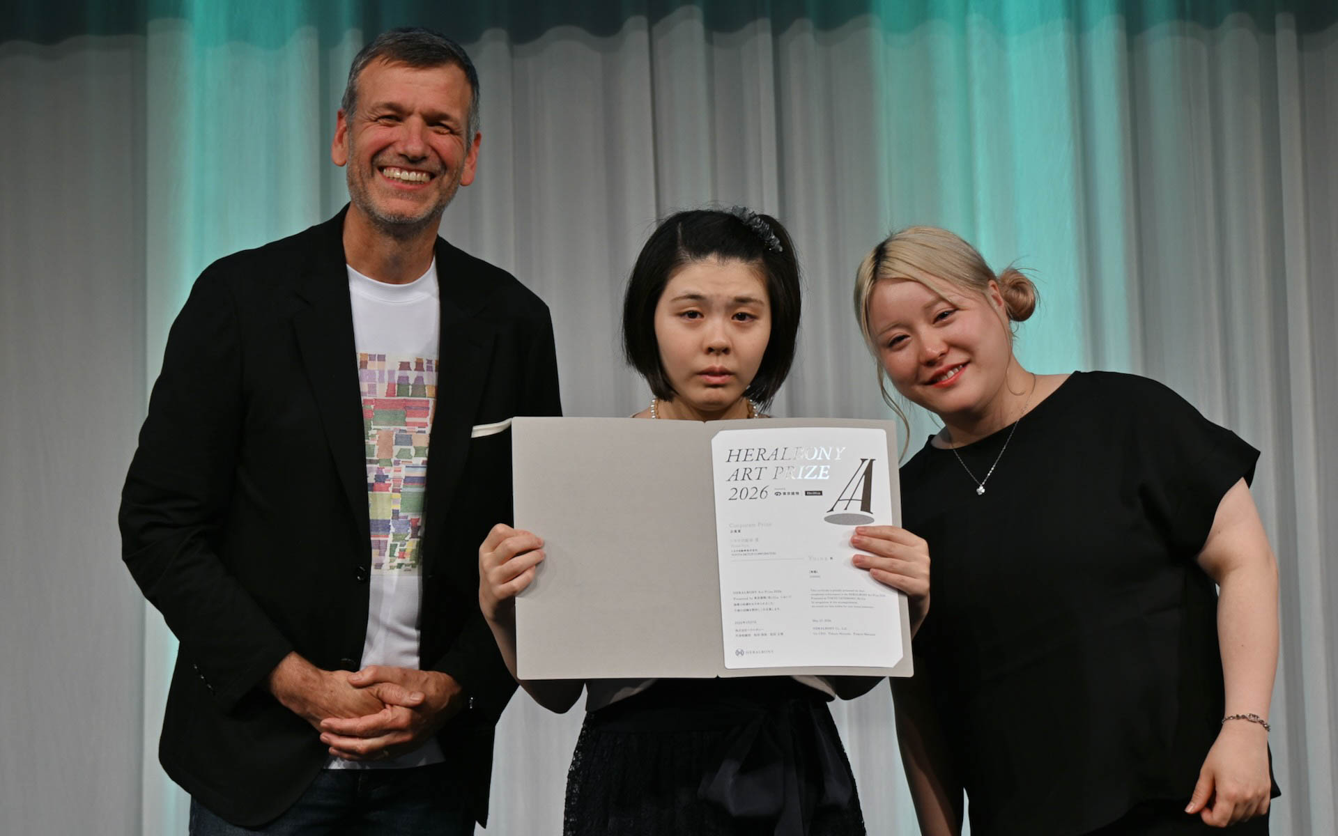 「HERALBONY ArtPrize 2026」でトヨタ自動車賞を受賞したYuina氏（中央）と、トヨタ自動車のサイモン・ハンフリーズ氏（左）