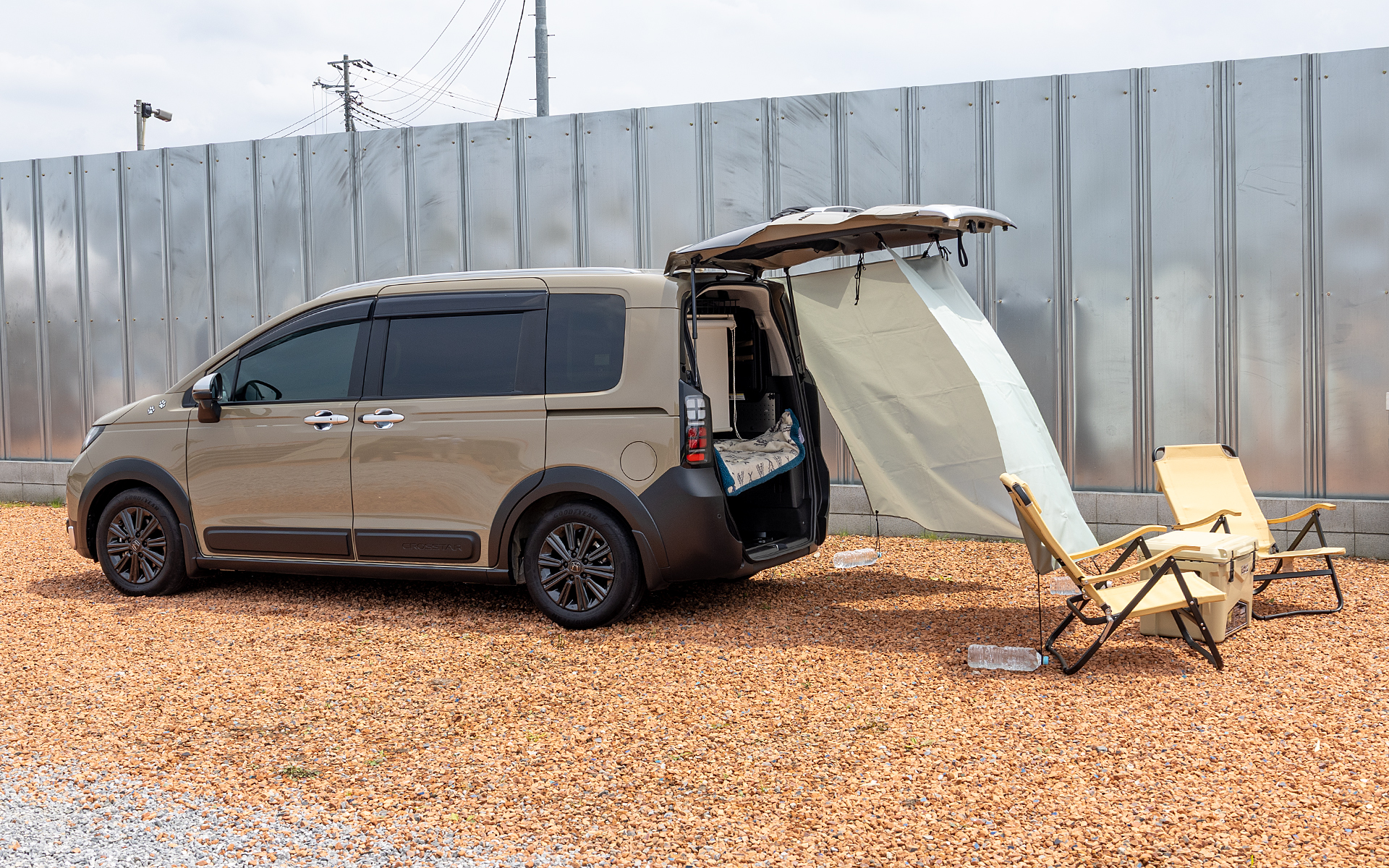 フリード e:HEV クロスターを使用した車中泊＆シアタールームの展示。「ボディサイドモール」（3万3000円）、「アルミホイール MG-032」（3万2560円/本）、「ドアハンドルプロテクションカバー」（1万1000円）、「マッドガード」（1万5400円）などを装着