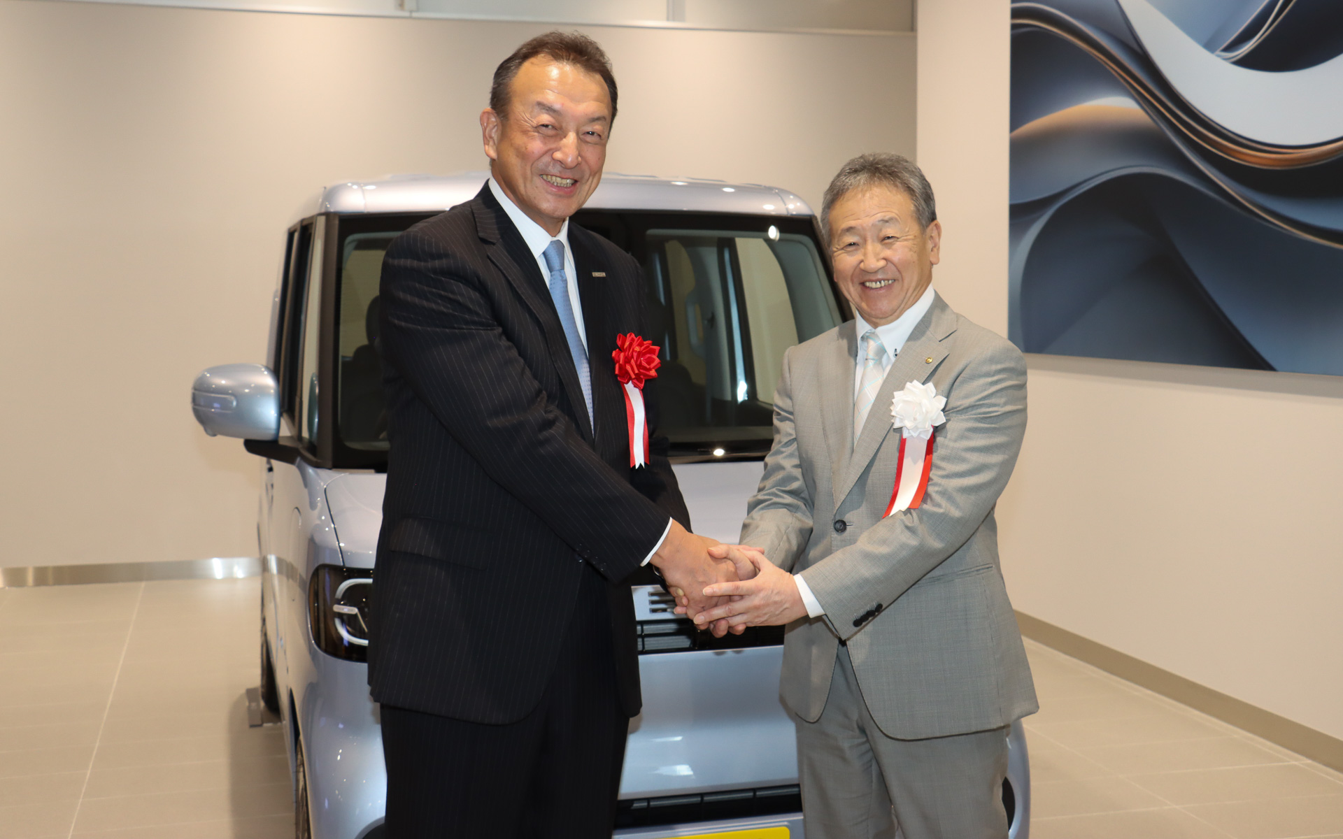 「ヤナセEVスクエア 磯子支店」（BYD AUTO 横浜南）開所式の最後に行なわれたフォトセッションで、笑顔で握手するBYD Auto Japan株式会社 代表取締役社長 東福寺厚樹氏（左）と株式会社ヤナセ 代表取締役社長執行役員 森田考則氏（右）