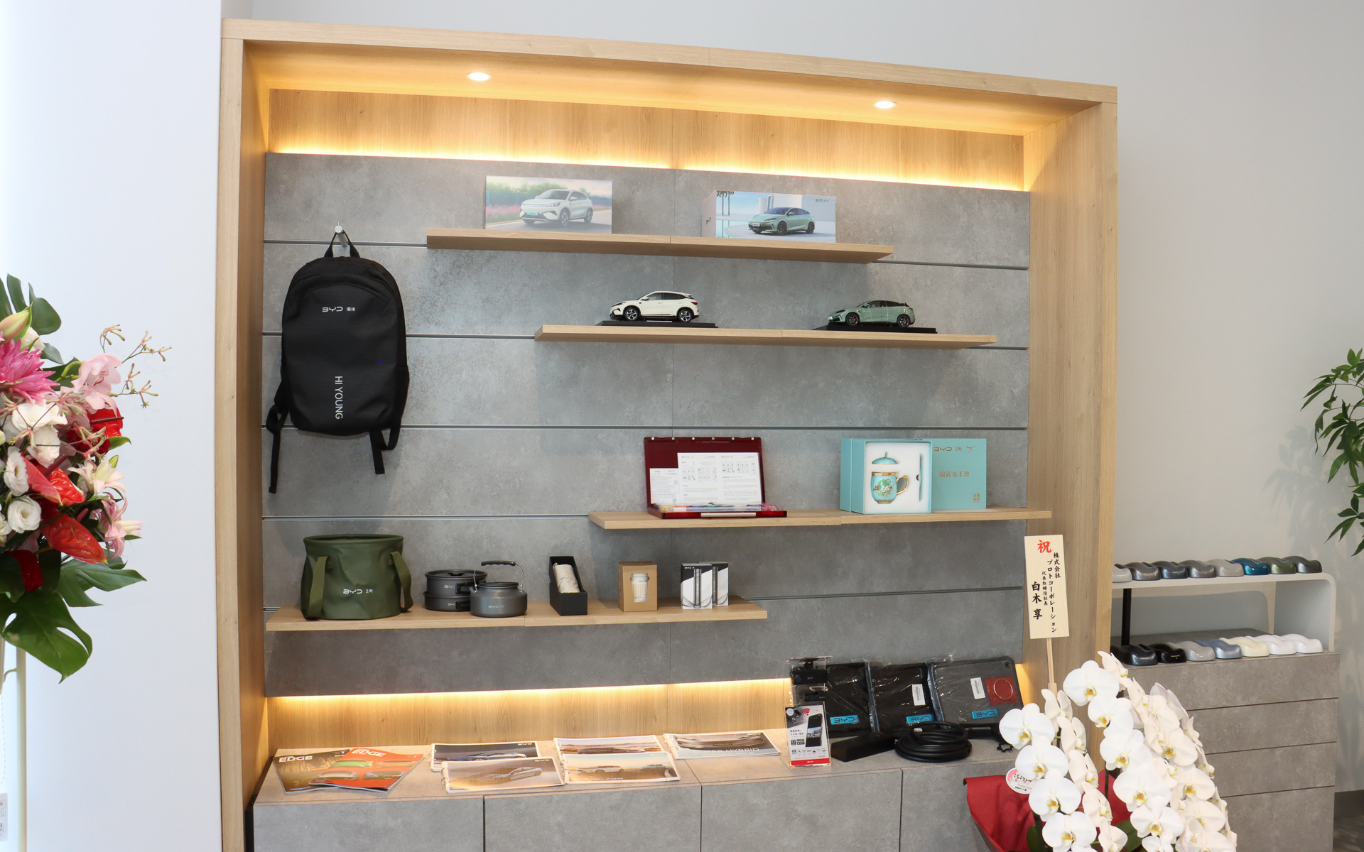 ショールームの一角に用意されたBYDグッズの展示コーナーには、純正ドライブレコーダーや「ACタイプV2Lアダプター」といったオプション品のほか、BYDのロゴ入りグッズも並ぶ