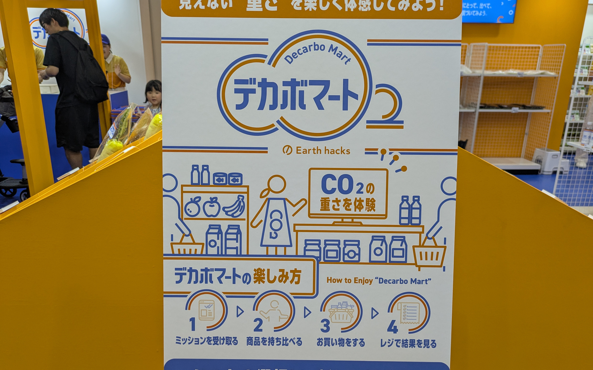 Earth hacksのブースでは、CO2 相当量に換算した値「CO2e」を従来の製品と比較し、削減率（％）を表示する「デカボスコア」を使い、見えないCO2の重みを体感できる買い物ごっこを楽しめる