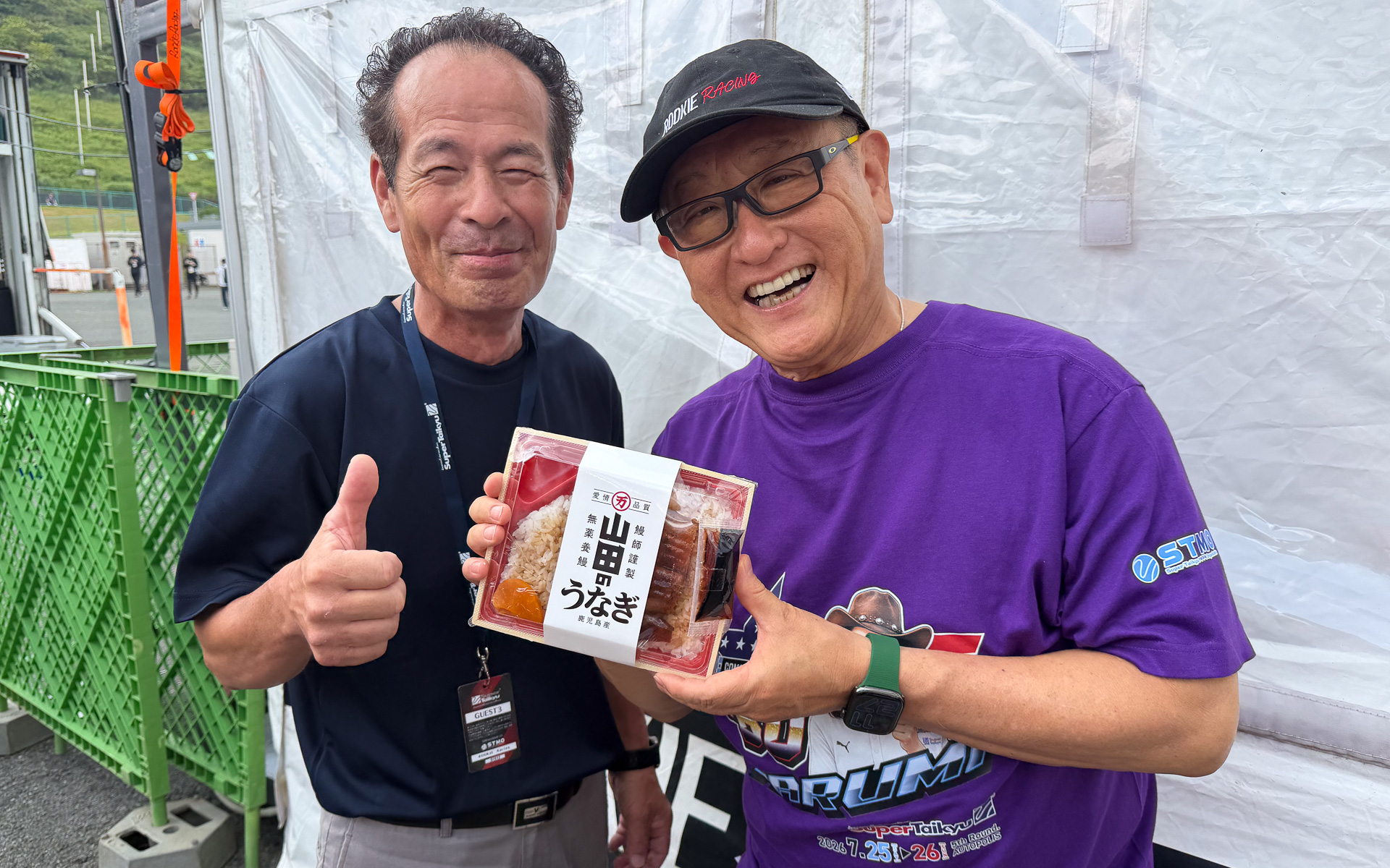 トヨタ自動車株式会社 代表取締役会長 豊田章男氏（右）。オートポリス戦での定番弁当は山田水産の「山田のうなぎ」弁当。常に商品をアピールすることを心掛けている自動車業界最強のインフルエンサー