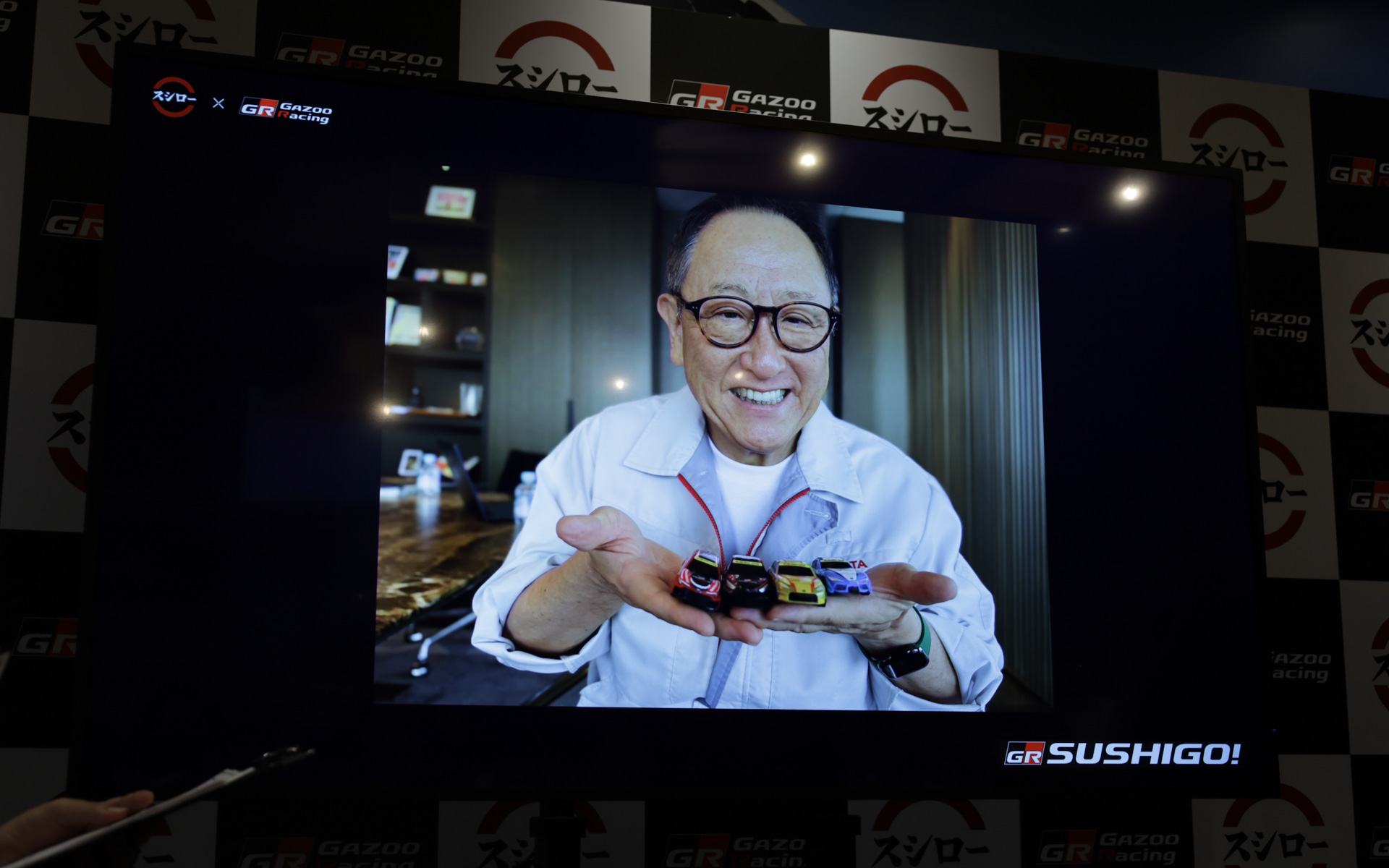コラボミニカーを手にするモリゾウことトヨタ自動車会長の豊田章男氏もモニターで出演