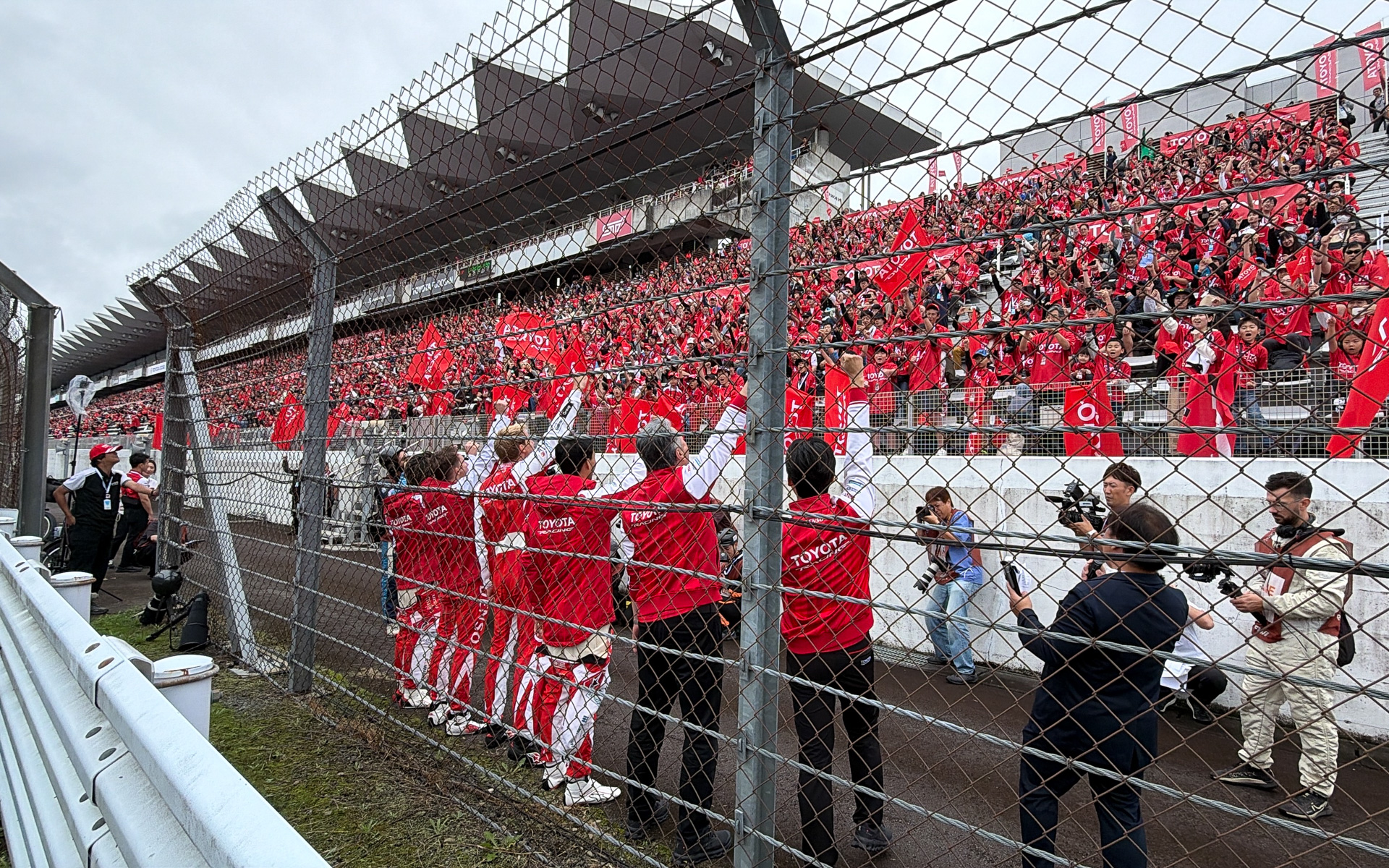 赤く染まるトヨタレーシングの応援席に向かって手を振る、トヨタレーシング ドライバーの面々