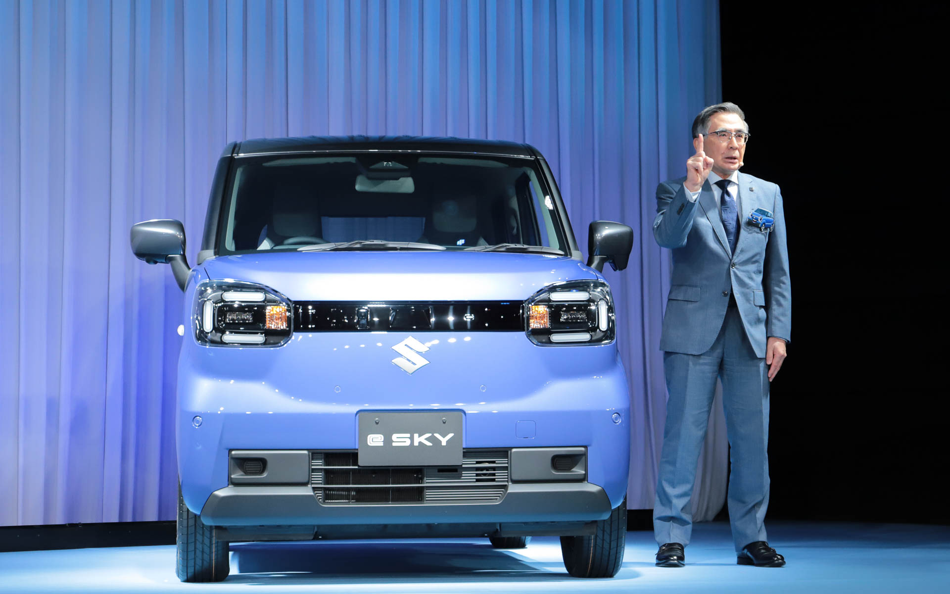新型e SKYの横でプレゼンテーションを行なう鈴木氏
