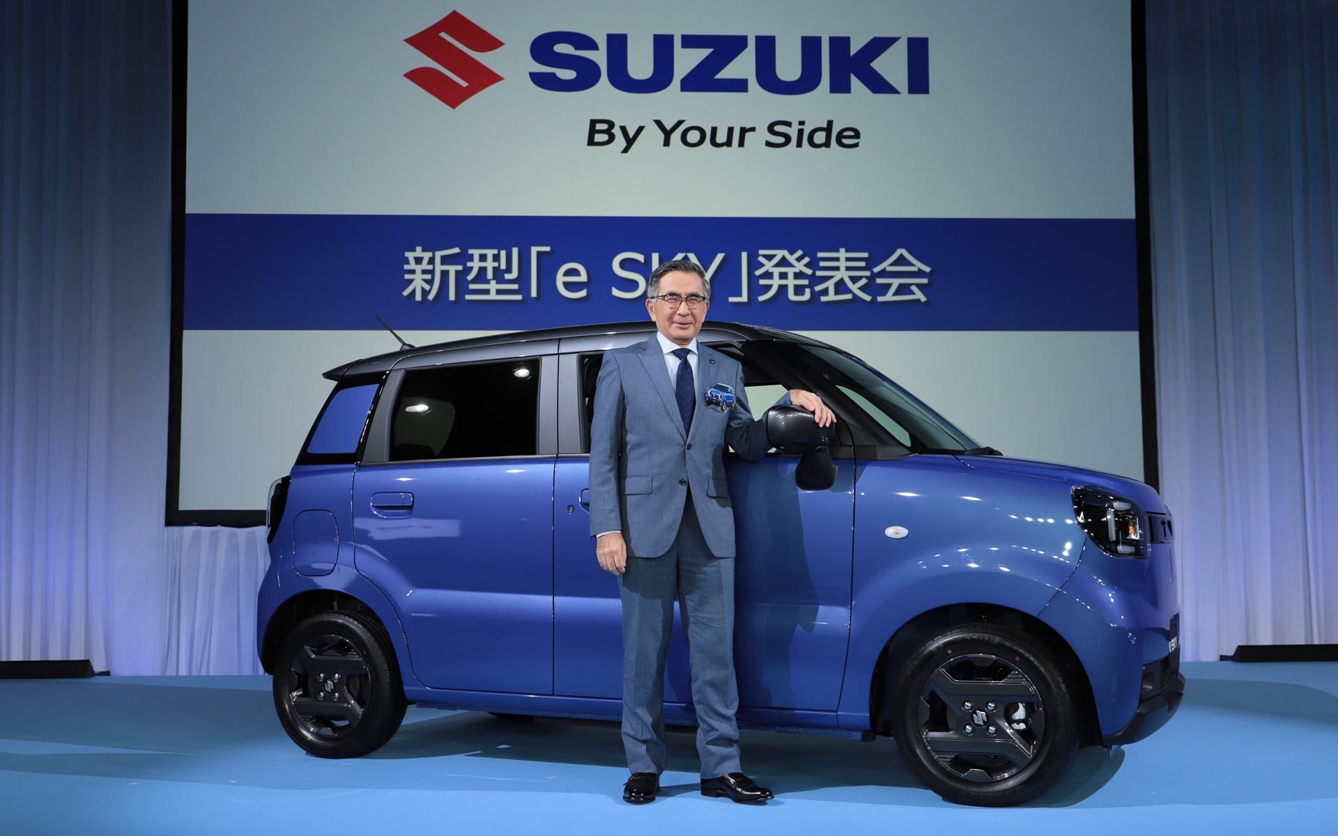 新型e SKYの横に笑顔で立つ鈴木俊宏氏
