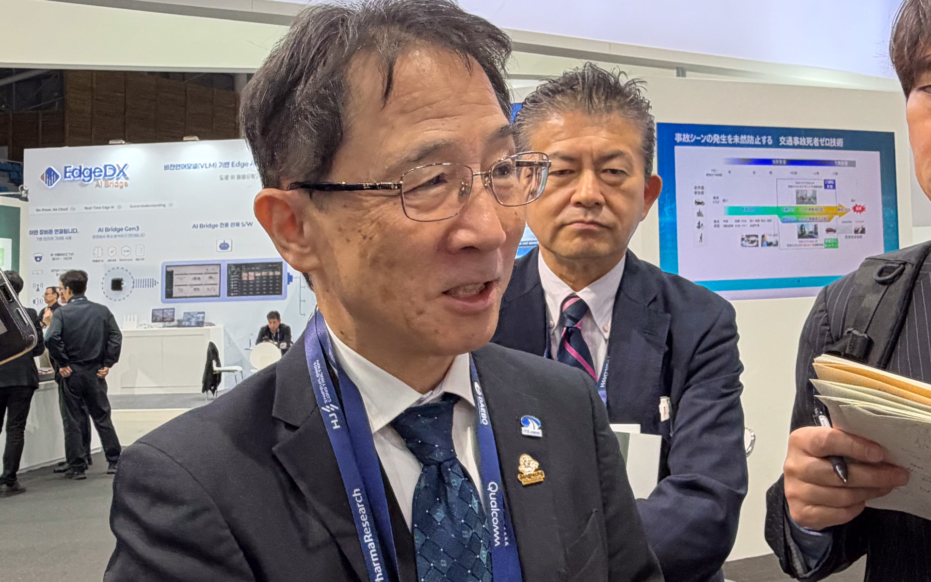 ITS Japanブースを前に報道陣の取材に応えるITS Japan会長 山本圭司氏