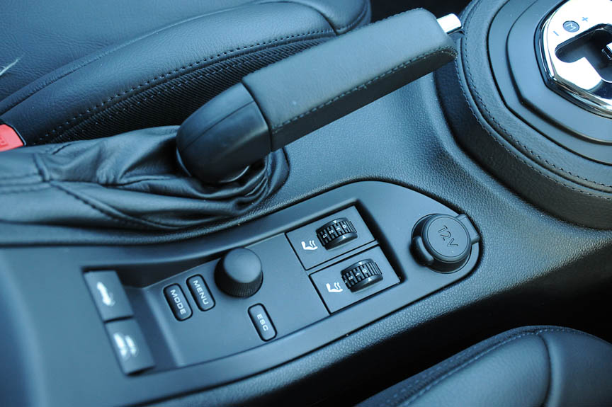 フロントシートのヘッドレスト下には「ネックウォーマー」を標準装備（写真右）。ここから温風が吹き出し、オープン時のドライブを快適にする。方向と温度（風量）は3段階で変更でき、メインのエアコンとは独立して制御できる。シフトレバーの後ろにコントロールスイッチがある