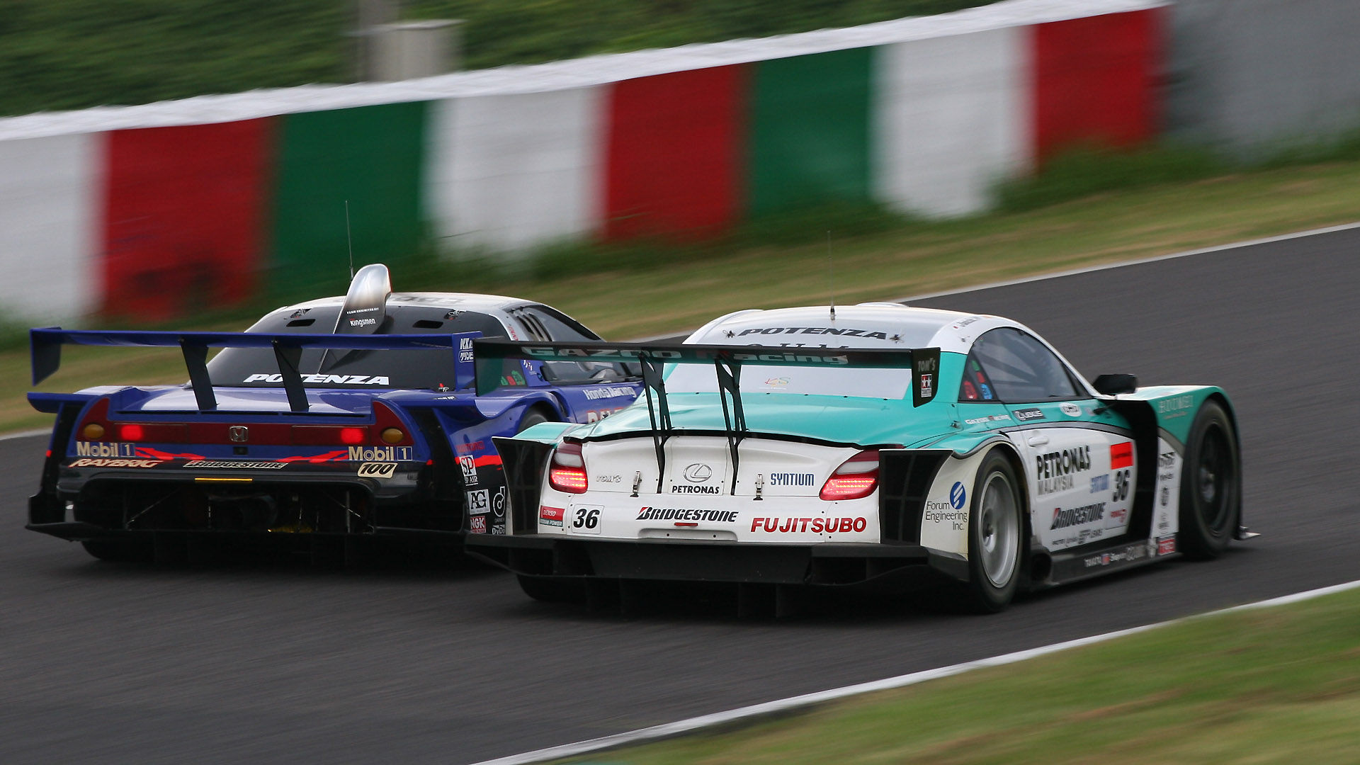 200mm（320mm相当） 1/80秒 F9。同じレースでヘアピンの立ち上がりを斜め後ろから撮影。ヘアピンの進入から立ち上がりまでシャッター速度1/80秒で連写した1枚（クリックすると1920×1080ピクセルの画像が開きます）