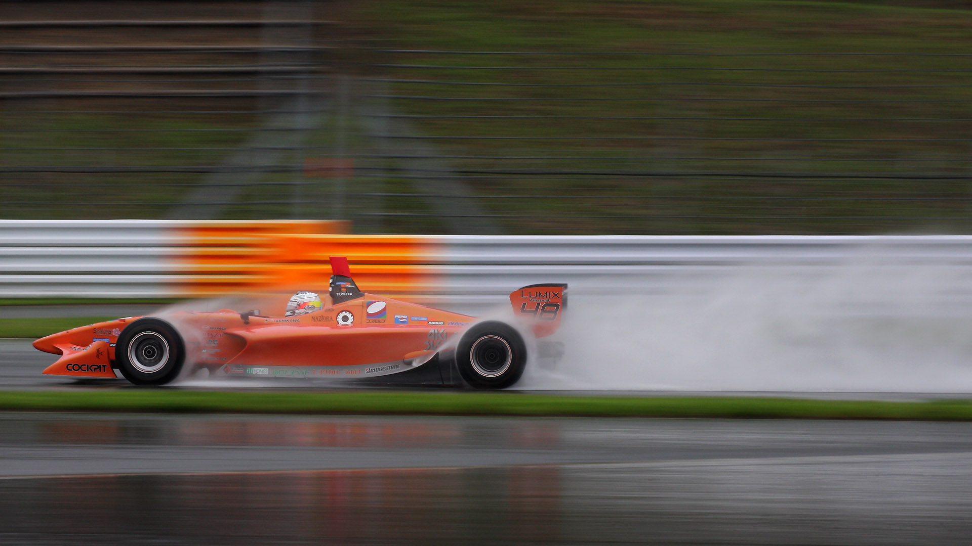 100mm（160mm相当） 1/160秒 F8。フォーミュラ・ニッポン第4戦富士。雨のレースで水煙を意識してマシンを左端に小さくフレーミング。雨の撮影は辛いが、雨でしか撮れない絵がある（クリックすると1920×1080ピクセルの画像が開きます）