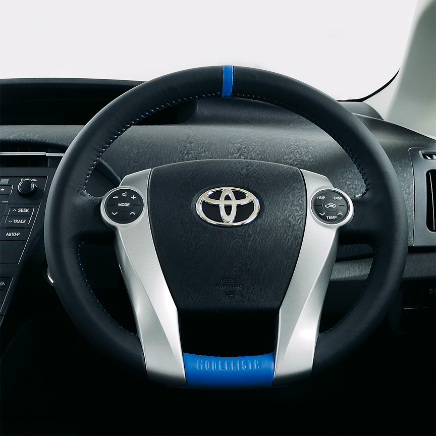 「レザーステアリング」。プリウスシンボルカラーをコーディネート。センターマーク部またはグリップ部をブルーにした2パターンのモデルを用意。いずれもベーストリムカラーにグレーまたはブラックを設定し、それぞれにモデリスタのロゴが入る。全グレード適合、2万7300円