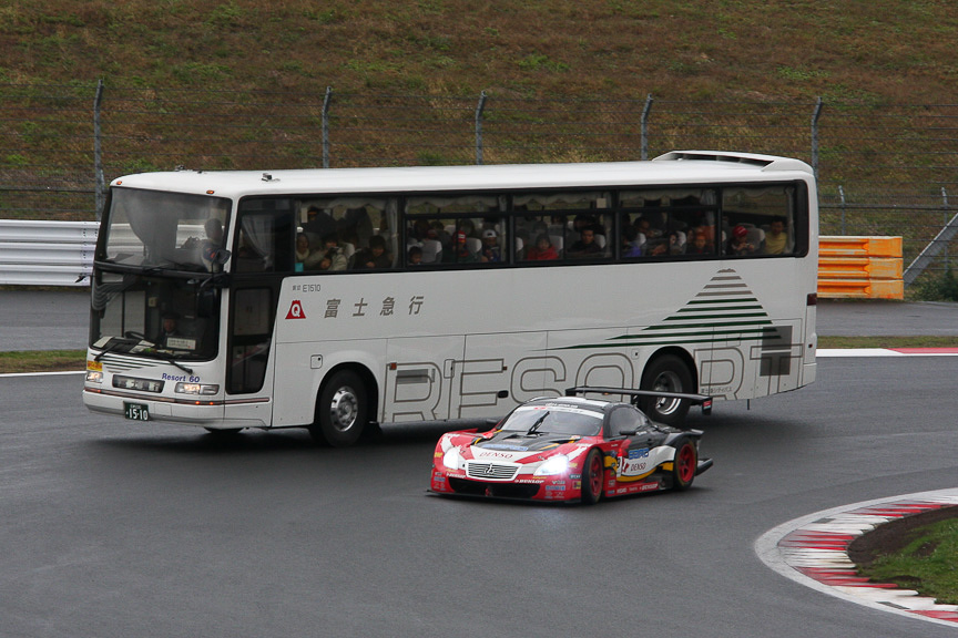 サーキットサファリで観光バスの横を抜いていくSUPER GTマシン。39号車「DUNLOP SARD SC430」