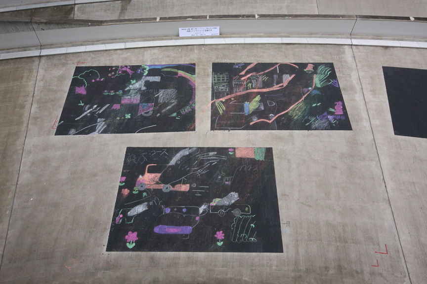 地元の小学生らが書いたイラスト。テーマは未来の自動車と未来の道。この上から表層されるため、イラストはずっと道路の下に残り続ける