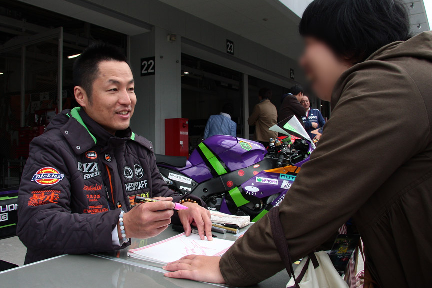 ピットウォークで写真撮影やサインをする出口選手