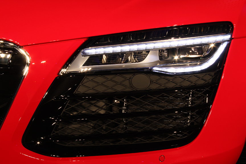 R8のデザインアイデンティティでもあるシングルフレームグリルとフルLEDヘッドライトの組み合わせ。従来は外側にロービーム、内側にハイビームを配置していたが、今モデルから最上段がロービーム、ポジショニングランプ＆ウインカーを挟んで下段がハイビームというレイアウトに変更された