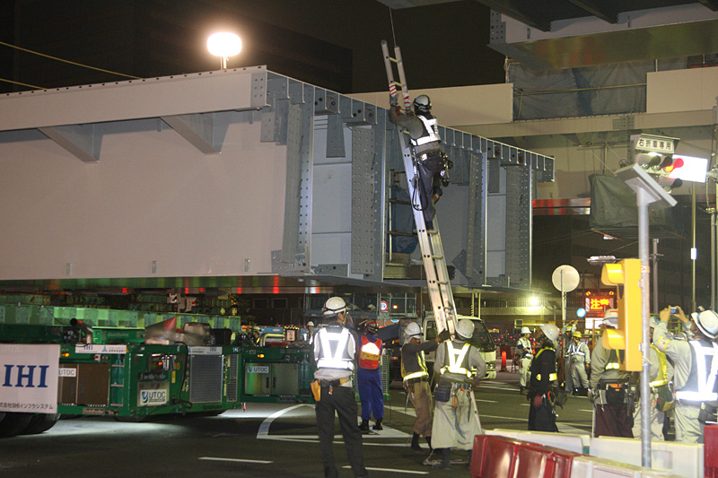 作業員がハシゴで架設桁に上がり吊り上げの準備を開始