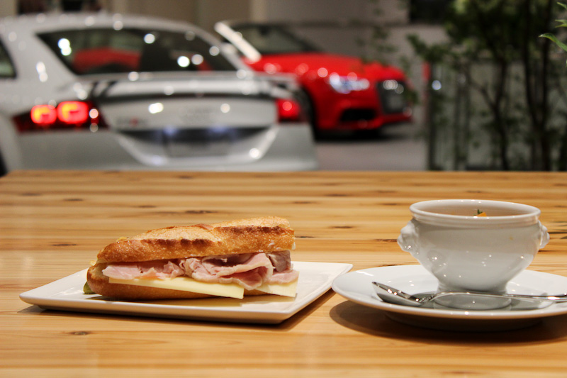 カフェスペースはショールームならではの広い空間、高い天井、大きな採光窓を活かして、木々の伸び伸びとした安らぎの雰囲気を演出。店内にはオリジナルの角材を使った大型テーブルが配置される