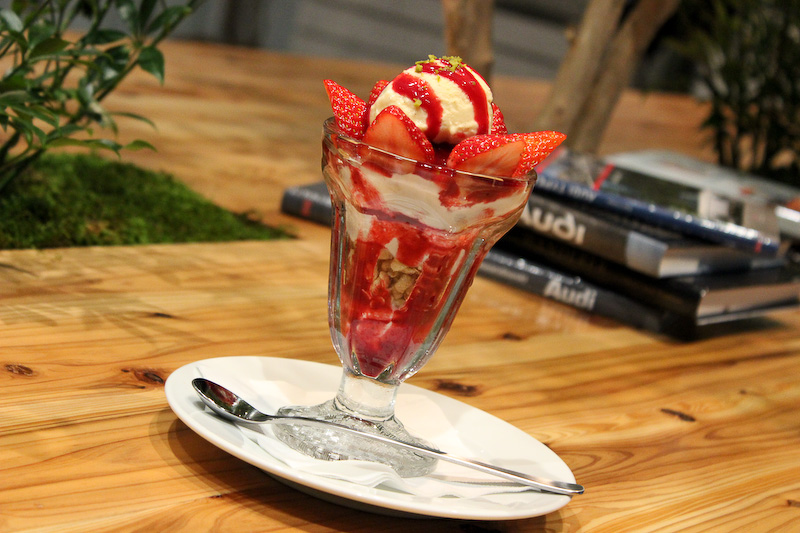 カフェスペースはショールームならではの広い空間、高い天井、大きな採光窓を活かして、木々の伸び伸びとした安らぎの雰囲気を演出。店内にはオリジナルの角材を使った大型テーブルが配置される