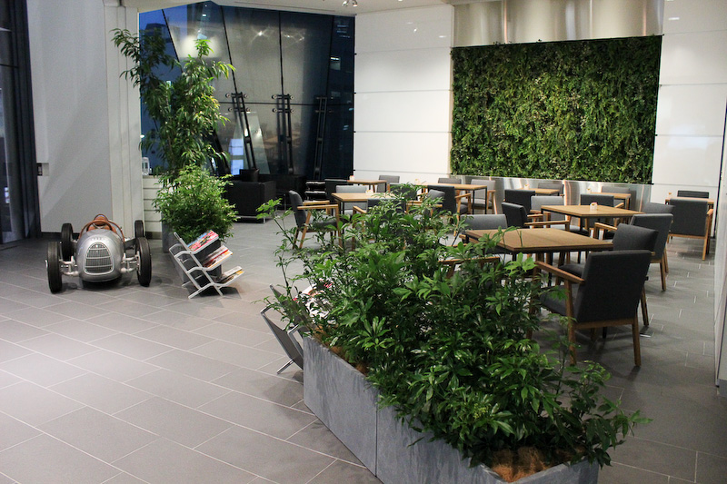 カフェスペースはショールームならではの広い空間、高い天井、大きな採光窓を活かして、木々の伸び伸びとした安らぎの雰囲気を演出。店内にはオリジナルの角材を使った大型テーブルが配置される