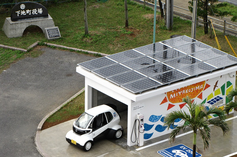 下地庁舎のPV充電ステーション。壁面の絵は宮古島市立下地小学校の6年生の手によるもの。MC-βは「走る姿がカワイイ」という感想が圧倒的に多く、下地小学校の生徒のみんなから愛されていた