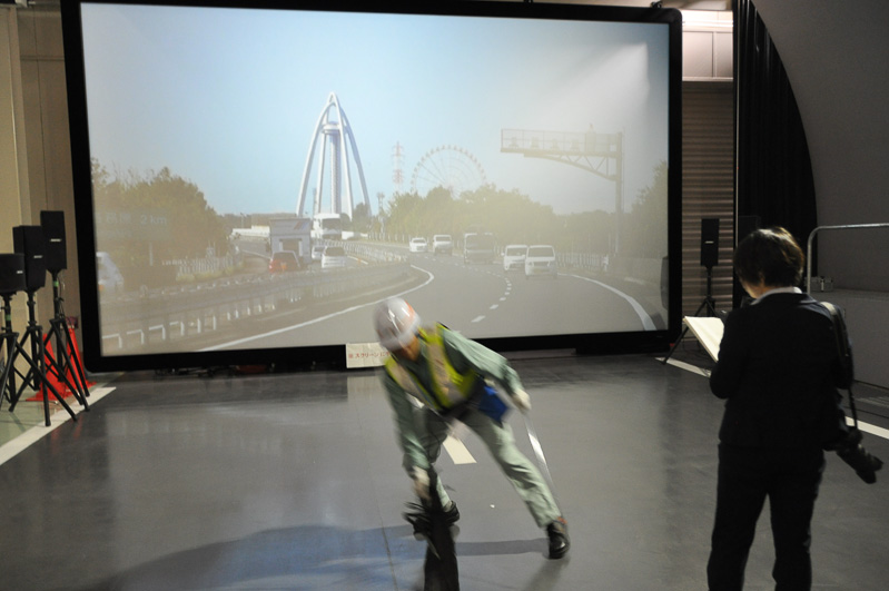 高速道路の落下物を取り除く訓練エリア。330インチのスクリーンに投影されるクルマのタイミングを見極めて飛び出す
