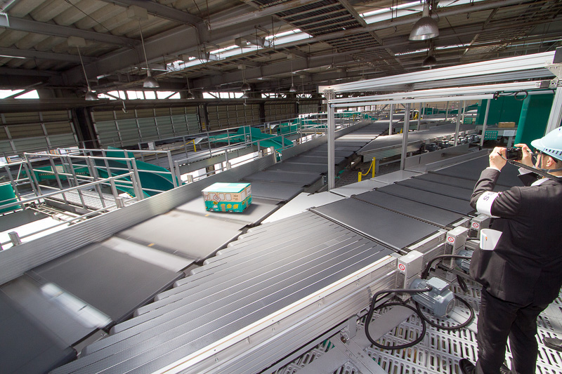 2階のクロスベルトソーター。1つのキャリアに1つの荷物が載せられる仕組みなので、荷物同士がぶつかる心配がない。仕分け場所に来るとコンベアが回転し、荷物をシュートに落とす。ルート上には荷物の片寄りを修正するゲートや赤外線装置もある