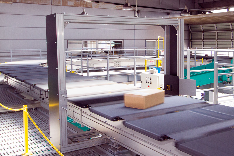 2階のクロスベルトソーター。1つのキャリアに1つの荷物が載せられる仕組みなので、荷物同士がぶつかる心配がない。仕分け場所に来るとコンベアが回転し、荷物をシュートに落とす。ルート上には荷物の片寄りを修正するゲートや赤外線装置もある