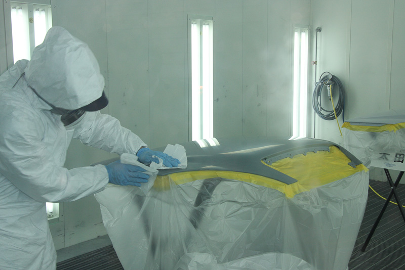 塗装開始前にブース内でボンネットを拭き上げてゴミの付着を防ぐ