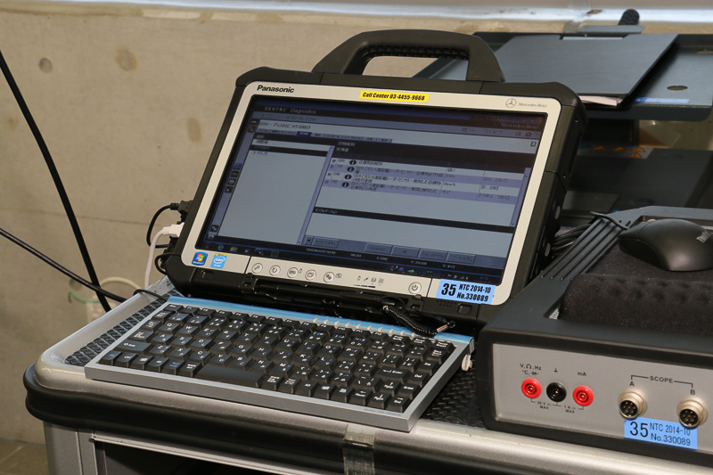 OBD2コネクターに診断機の車載器側をセット。液晶ディスプレイを備えるハンドセットとは無線を使ってデータをやりとりする。ハンドセットにはパナソニックのロゴが入っており、Windows OSで動作している