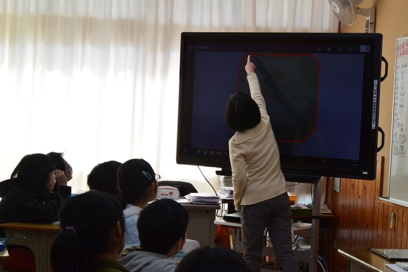 電子黒板を使って算数の授業を行う、嶺川由香教諭と5年2組の子どもたち。