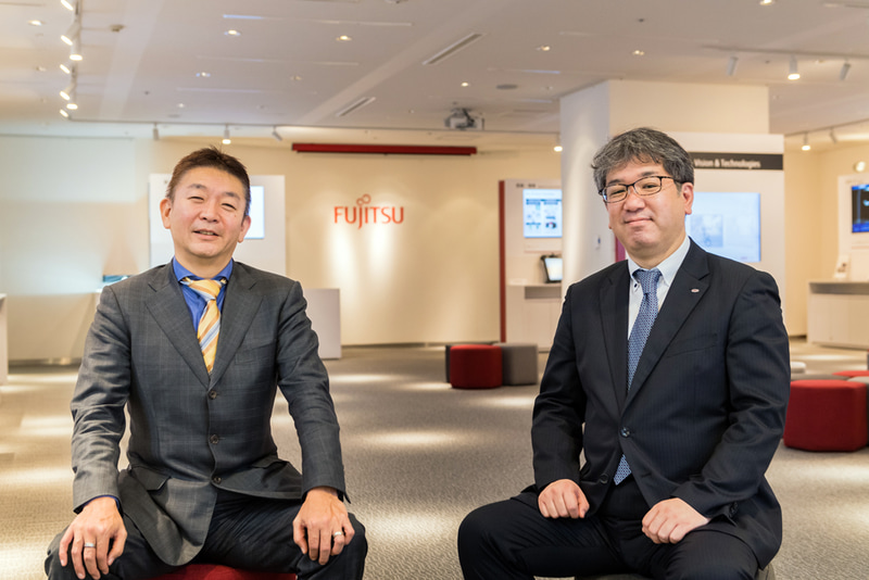 富士通の牧雄治郎本部長代理（右）と、日本AMDの林田裕代表取締役（左）