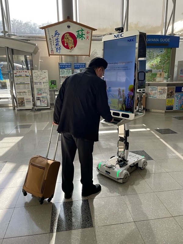 来訪者がロボットを操作して案内を受ける様子