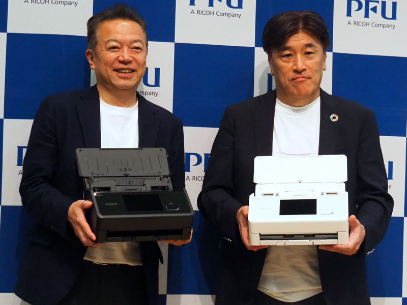 ScanSnap iX2500を手に持つ、宮内康範常務執行役員（左）と平原英治社長執行役員（右）