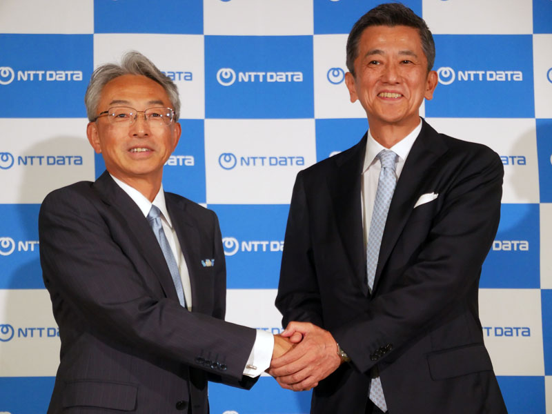 6NTTデータ 代表取締役社長の鈴木正範氏（右）、NTTデータグループ 代表取締役社長の佐々木裕氏。後ろの新ロゴは2025年7月から使用することになる