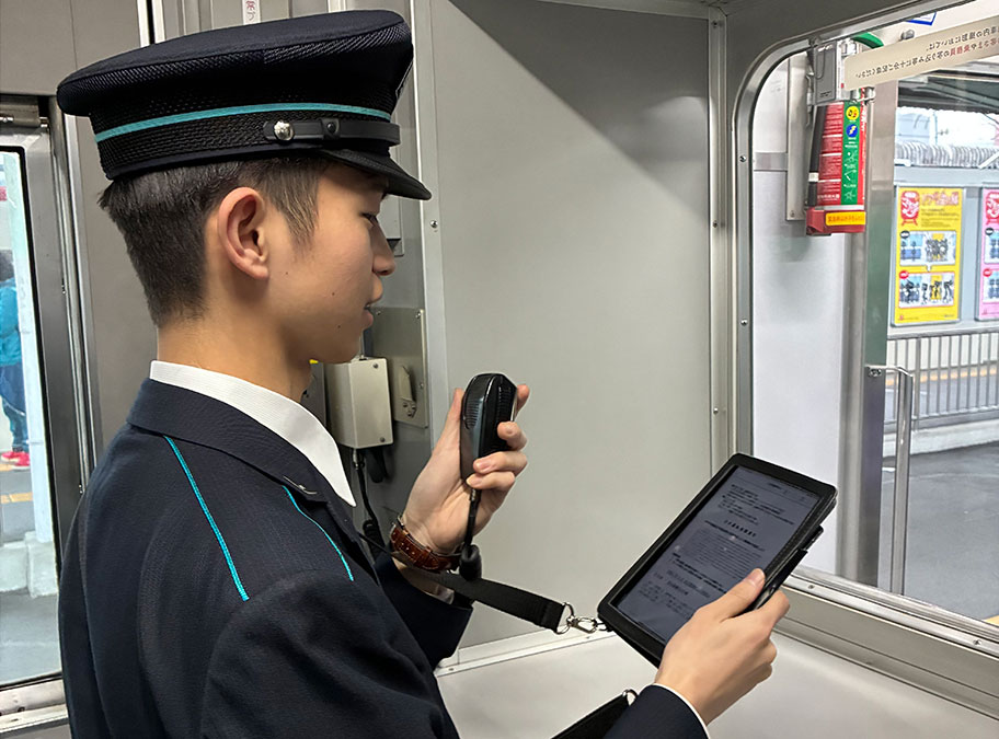 Handbook Xに登録した業務資料をもとに車内放送をする様子