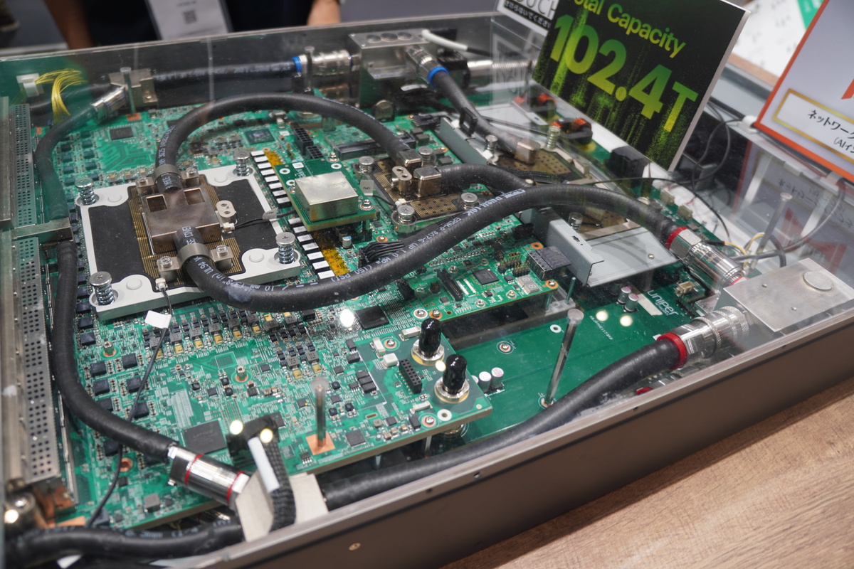 Juniper QFX5250-64OE-Lの上面を透明にした展示。液冷の配管が見える