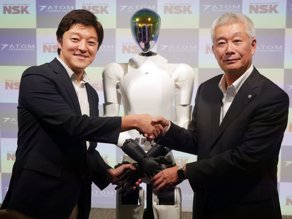 アトム 代表取締役社長の青木俊介氏（左）と日本精工 取締役代表執行役社長・CEOの市井明俊氏（右）、そして開発中のヒューマノイドAIロボット