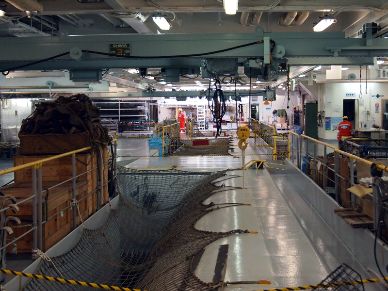 作業甲板。ほぼ船首から船尾ほどの広い空間だが、柱は一本もない。手前にある網のかかった穴の下には3基のケーブルタンクがある