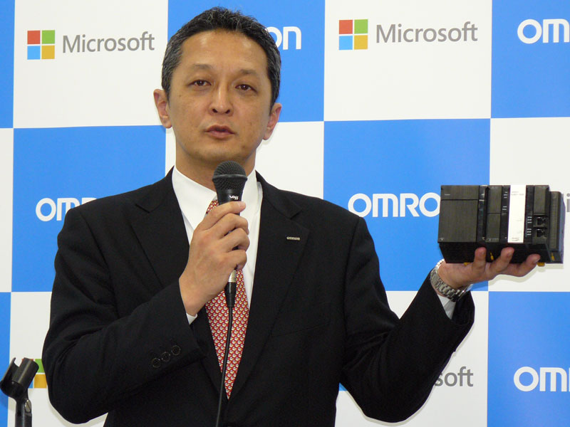 オムロン オートメーションシステム統轄事業部 コントロール事業部 副事業部長の横見光氏。手にしているのは新製品の「Sysmac NJシリーズ データベース接続CPUユニット」である