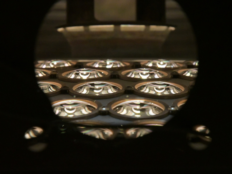 蒸着装置の覗き窓にレンズを押し当てて撮影。中でドームが回転している