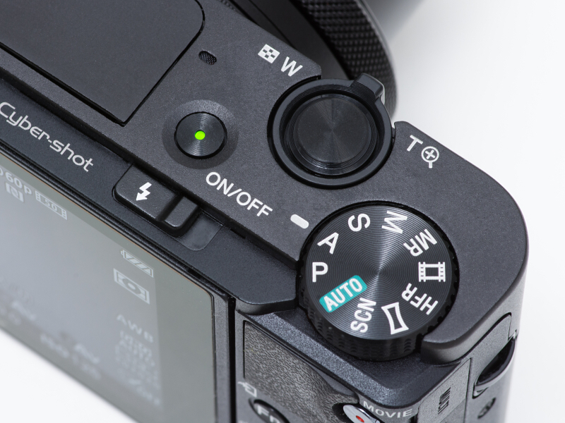 上面はモードダイヤルとシャッターボタン、ズームレバー、電源ボタンを備える。電源ボタンの後ろはフラッシュポップアップレバーだ。上部に出っ張りがなく、ほぼフラットな形をしている。