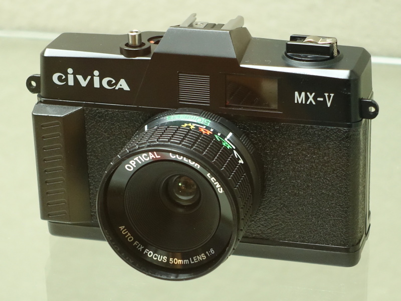 台湾の「シヴィカMX-V」（メーカー不明、1980年代半ば）。台湾ではトイカメラが盛んに作られた時期があり、その中でも比較的しっかりつくられたものだという。天気マークに合わせて絞りを操作するだけの固定焦点レンズと見られるが、銘板に「AUTO FIX FOCUS」とあるのが面白い。