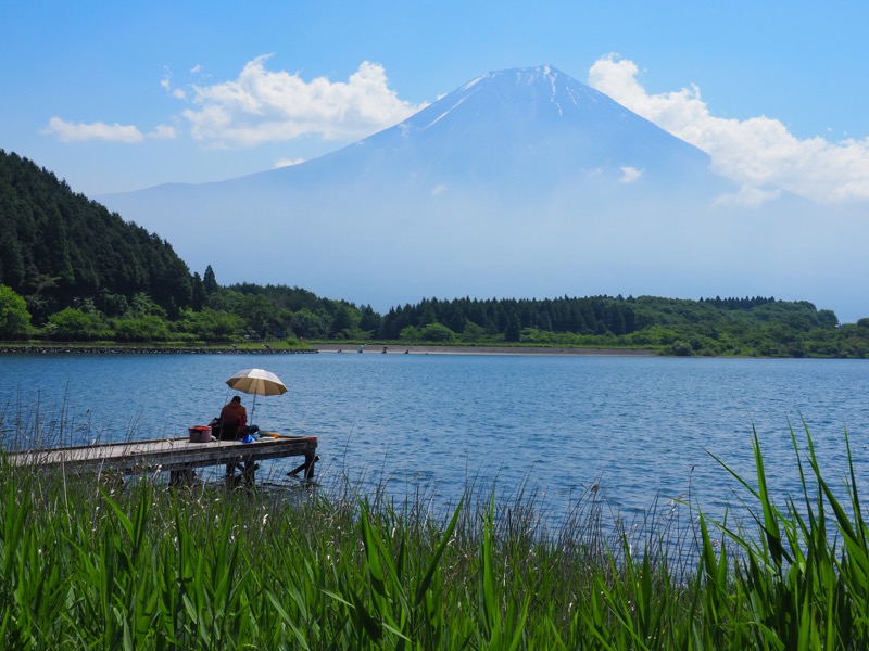 昼の田貫湖より釣り人と夏の富士山を絡めた風景を撮影した。人物を点景として取り込んだ物語性の高い写真においても、焦点距離を幅広く選べるので構図を作りやすい。<br><span class="fnt-85">OLYMPUS OM-D E-M1 Mark II / M.ZUIKO DIGITAL ED 12-100mm F4.0 IS PRO / 28mm（56mm相当） / マニュアル露出（F14、1/200秒） / ISO 800</span>