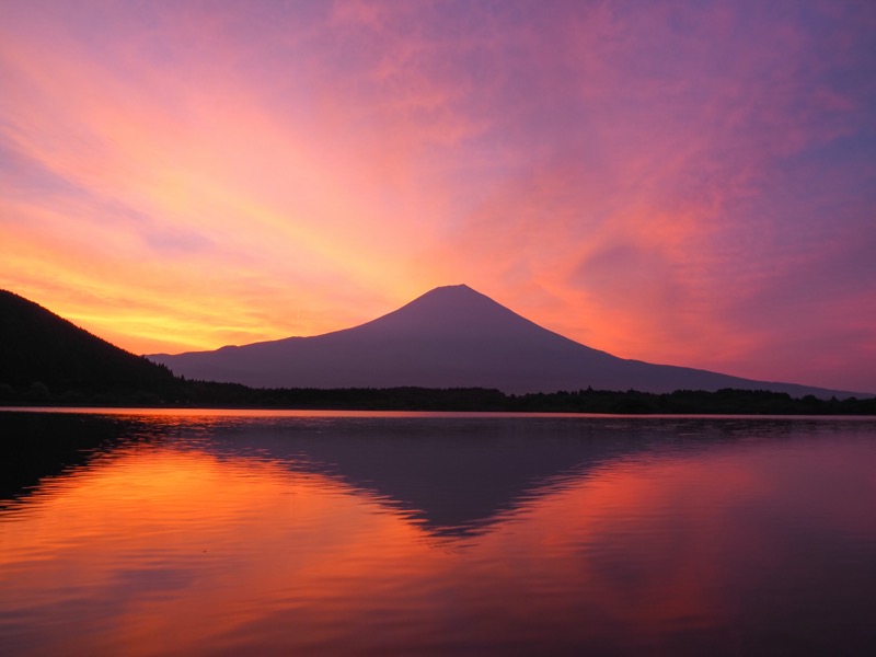 天気図を見て朝焼けを予感しながらスタンバイ。燃えるような朝焼けが画面いっぱいに広がった。広角端の12mmで朝焼けの空と富士山、映り込みを1枚で広く捉えた。<br><span class="fnt-85">OLYMPUS OM-D E-M1 Mark II / M.ZUIKO DIGITAL ED 12-100mm F4.0 IS PRO / 12mm（24mm相当） / マニュアル露出（F18、1/4秒） / ISO 200</span>
